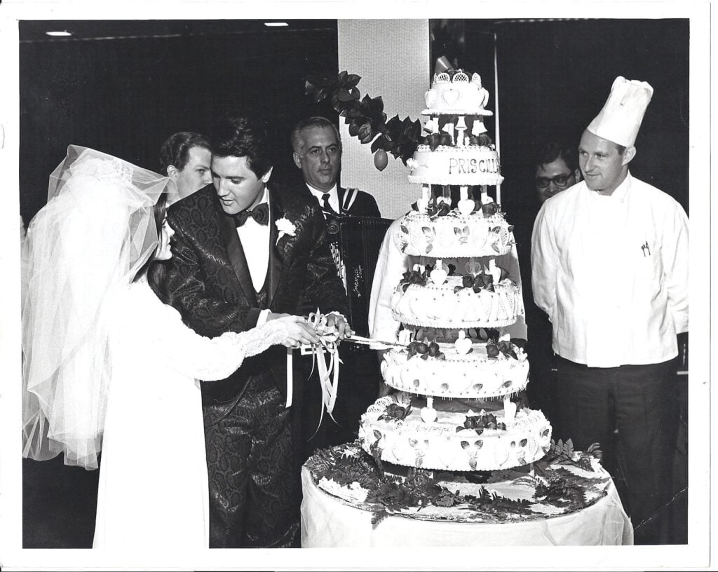 elvis and priscilla presley standing in front of their wedding cake