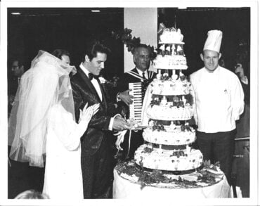 elvis and priscilla presley standing in front of their wedding cake